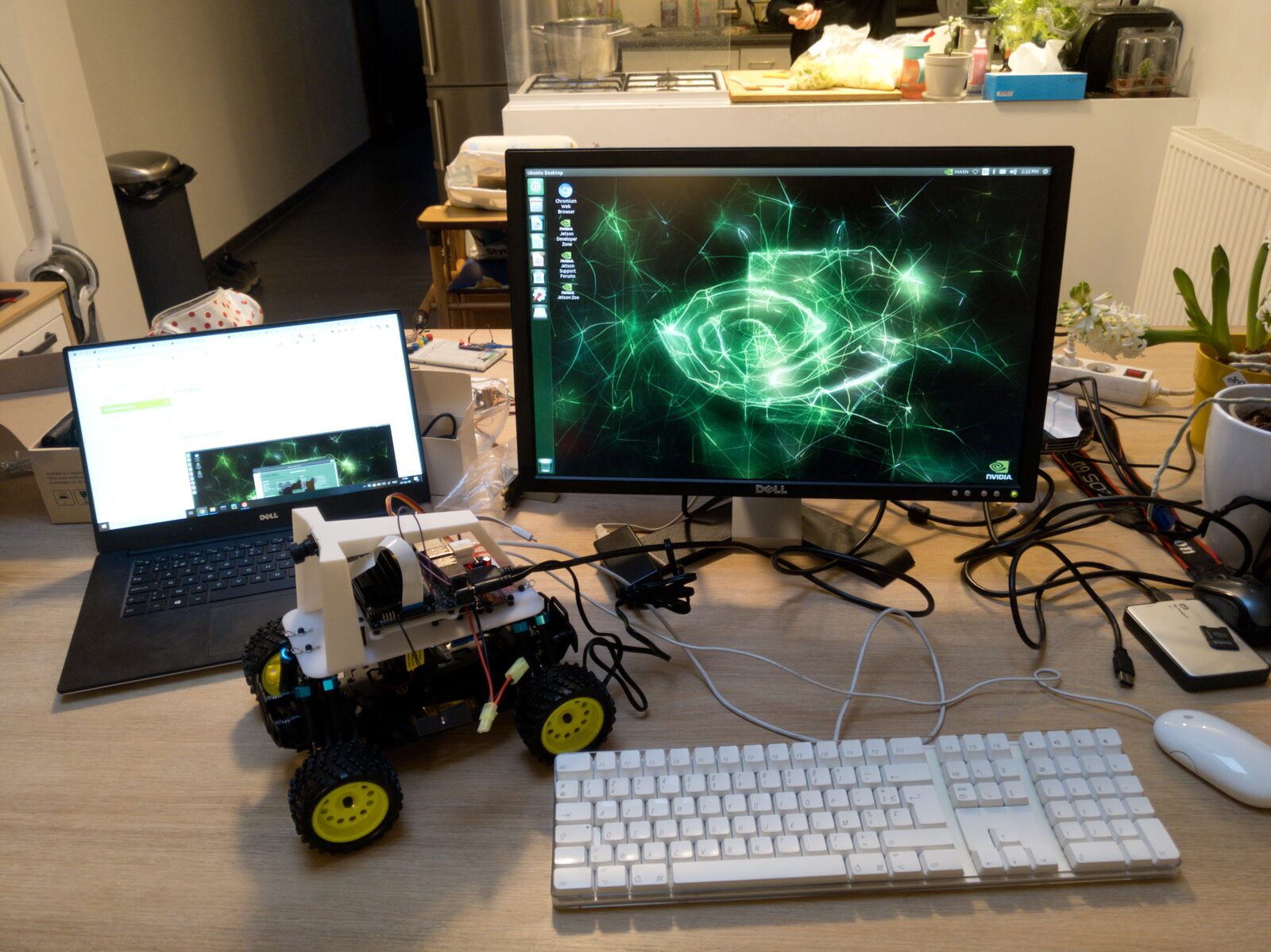 An assembled DonkeyCar — a Jetson Nano and camera on a white 3D-printed cage mounted on an RC car chassis — on a desk beside a monitor showing the NVIDIA Jetson Ubuntu desktop